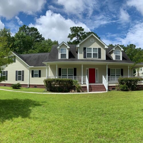 exterior-painting-mountpleasant-hardie-siding A large white house with red door and green grass.