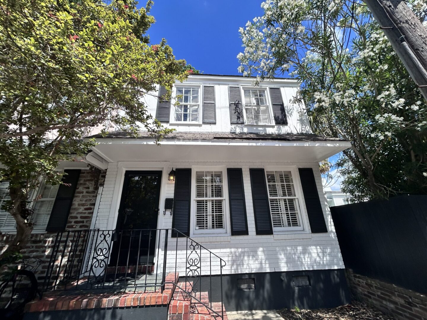 A white house with black shutters and a black door.