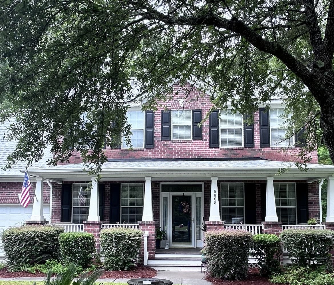 A large brick house with black shutters and white trim.