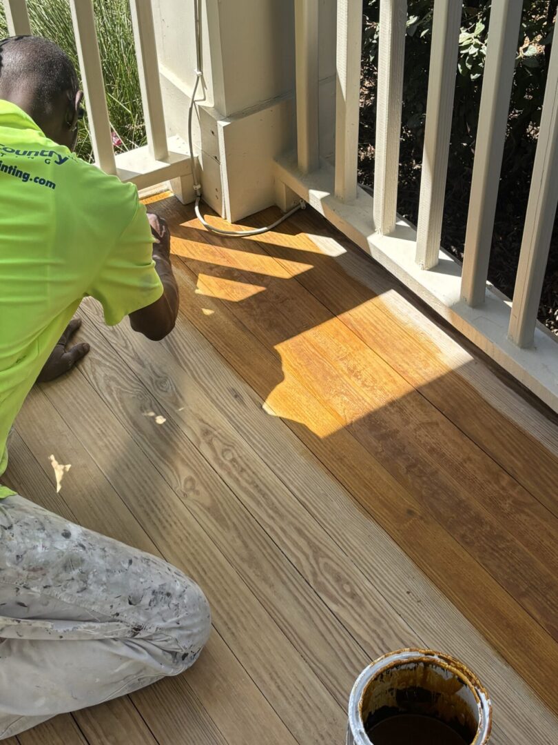 Low Country Painting crew member applying DEFY semi-transparent stain to a porch floor in Summerville, SC.