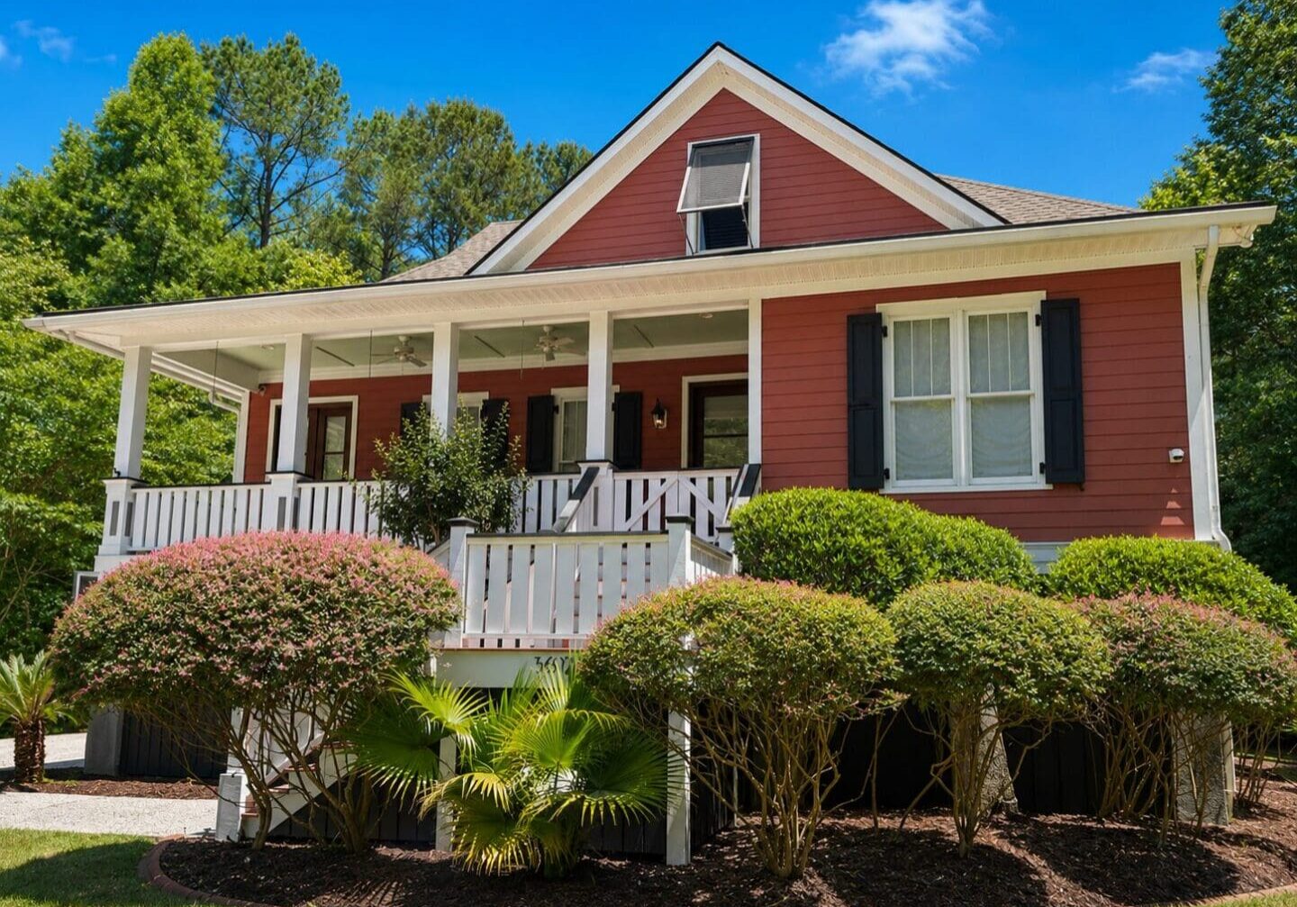 Professional exterior house painting in Charleston, SC featuring red siding, crisp white trim, and black shutters.