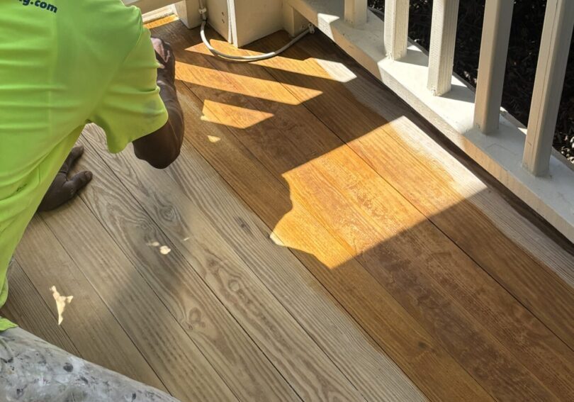 Low Country Painting crew member applying DEFY semi-transparent stain to a porch floor in Summerville, SC.
